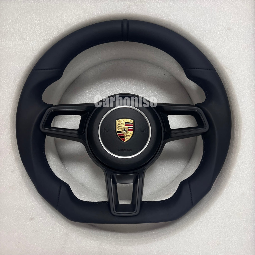Custom Porsche performance steering wheel featuring a full black smooth leather wrap and the Porsche gold and black crest.