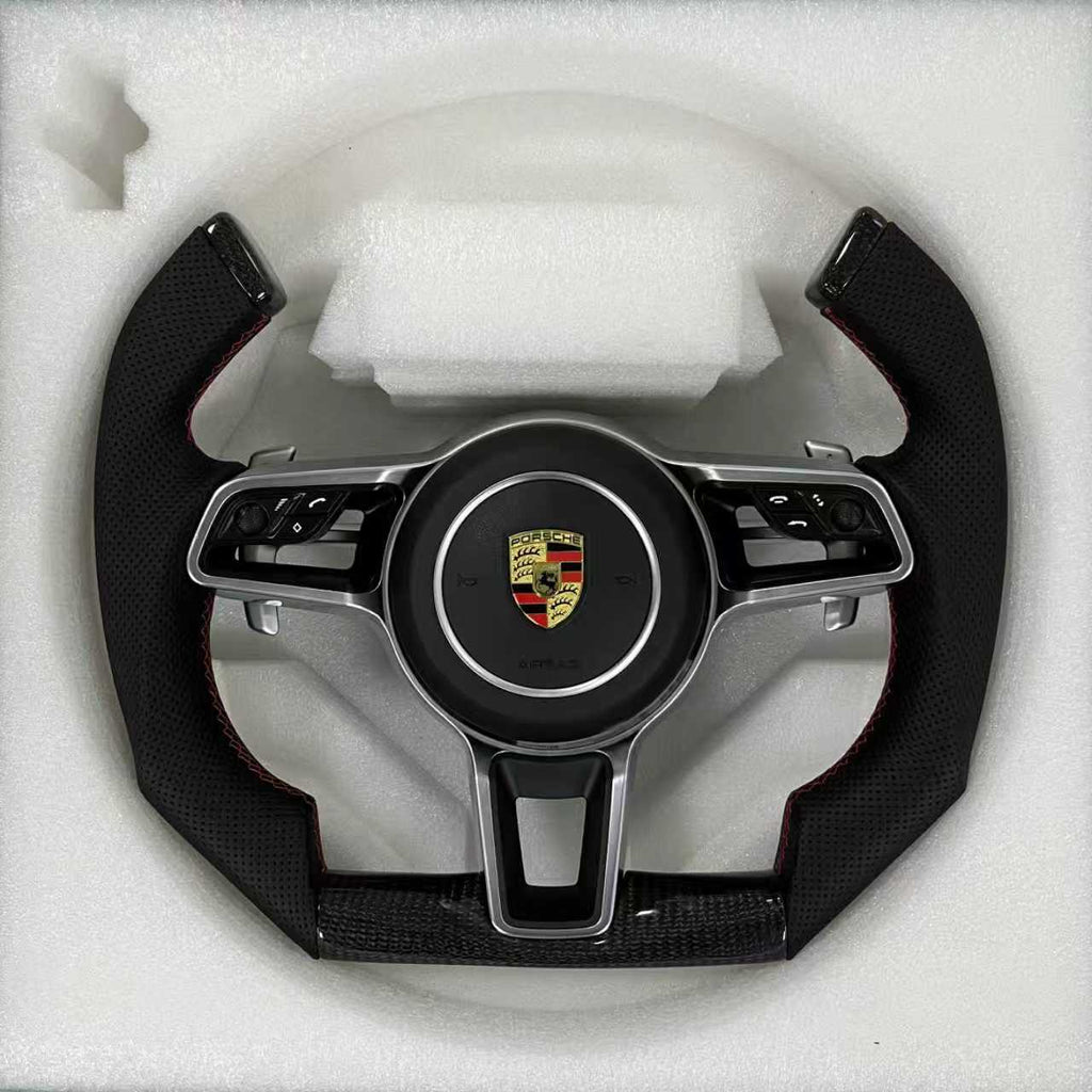 Custom Porsche performance steering wheel featuring an open-top yoke design with high-gloss carbon fiber and black perforated leather side grips.