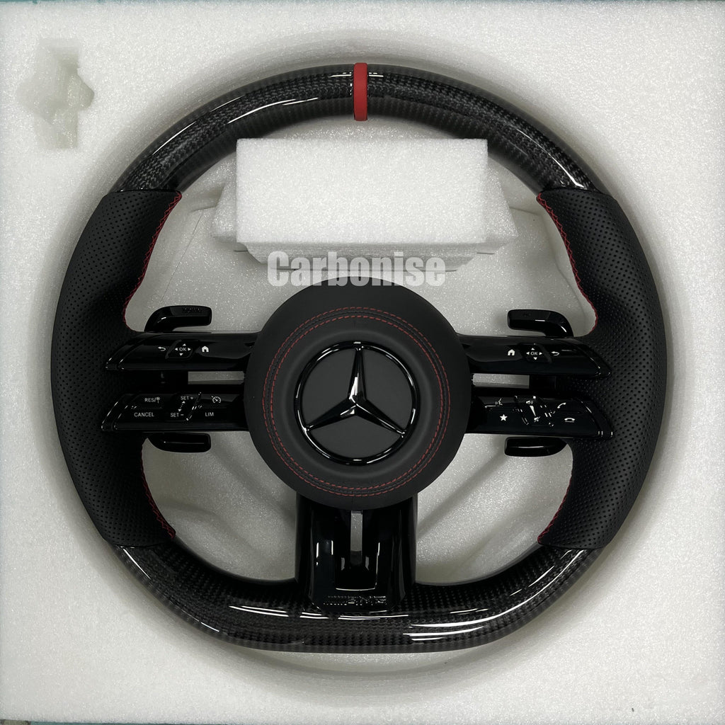 Custom Mercedes-Benz AMG steering wheel featuring high-gloss carbon fiber, a red top racing stripe, and black perforated leather grips with red stitching.