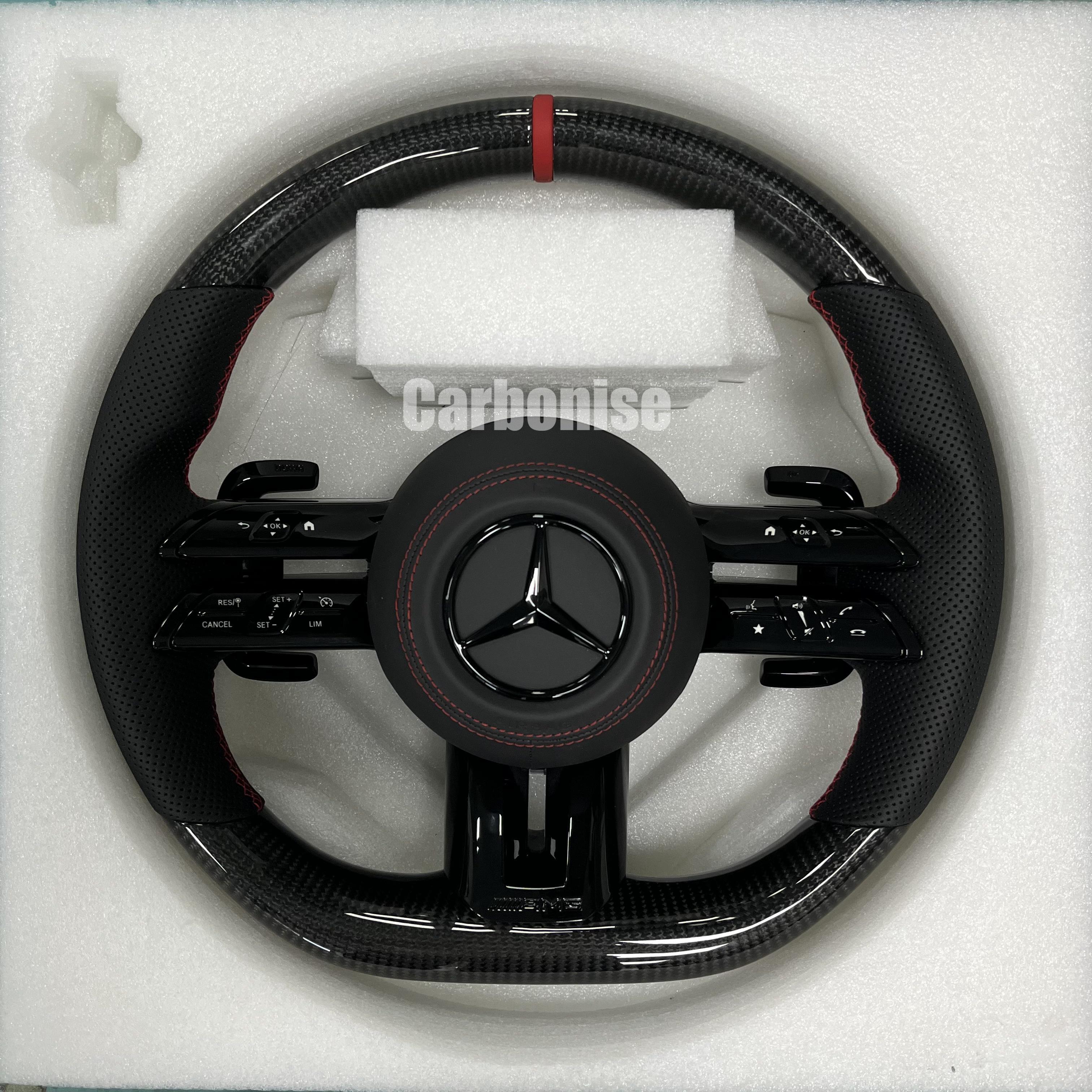 Custom Mercedes-Benz AMG steering wheel featuring high-gloss carbon fiber, a red top racing stripe, and black perforated leather grips with red stitching.