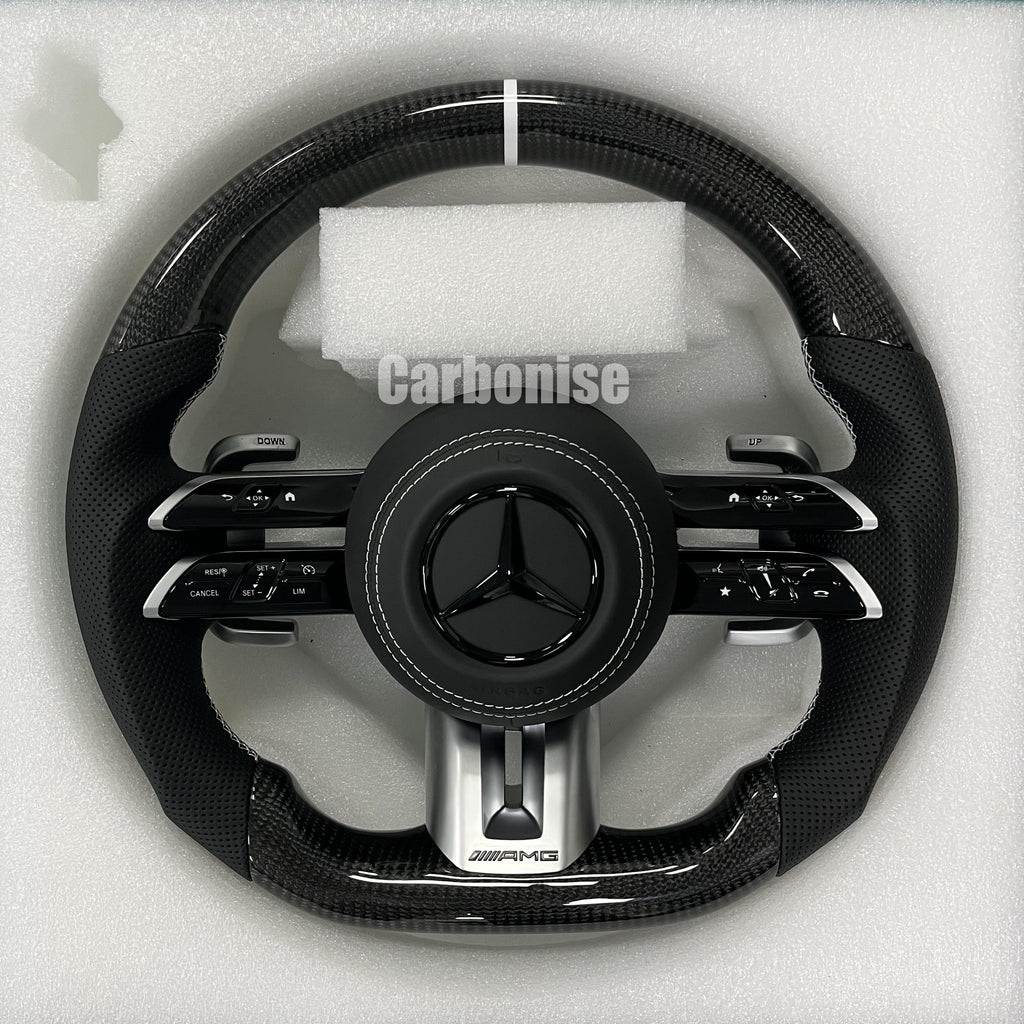 Custom Mercedes-Benz AMG steering wheel featuring high-gloss carbon fiber, a silver top racing stripe, and black perforated leather grips with white stitching.