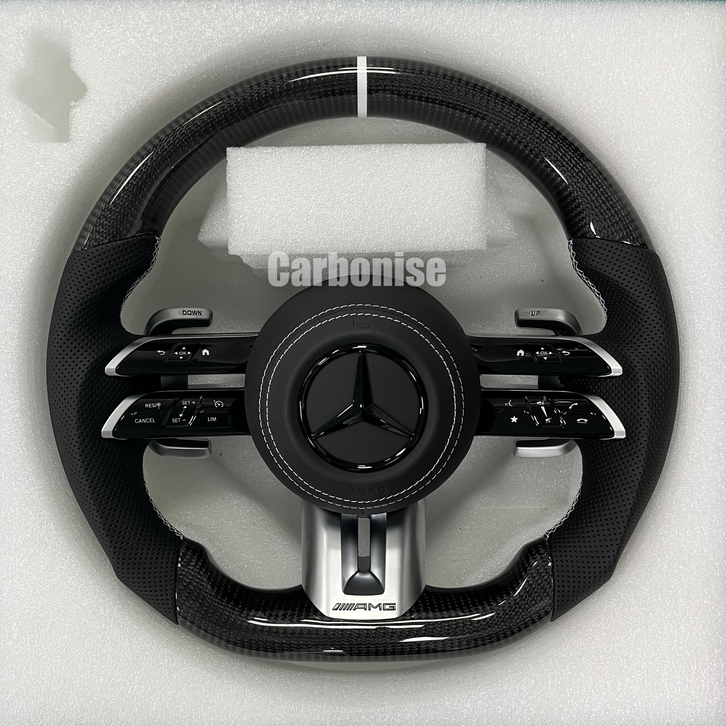Custom Mercedes-Benz AMG steering wheel featuring high-gloss carbon fiber, a silver top racing stripe, and black perforated leather grips with white stitching.