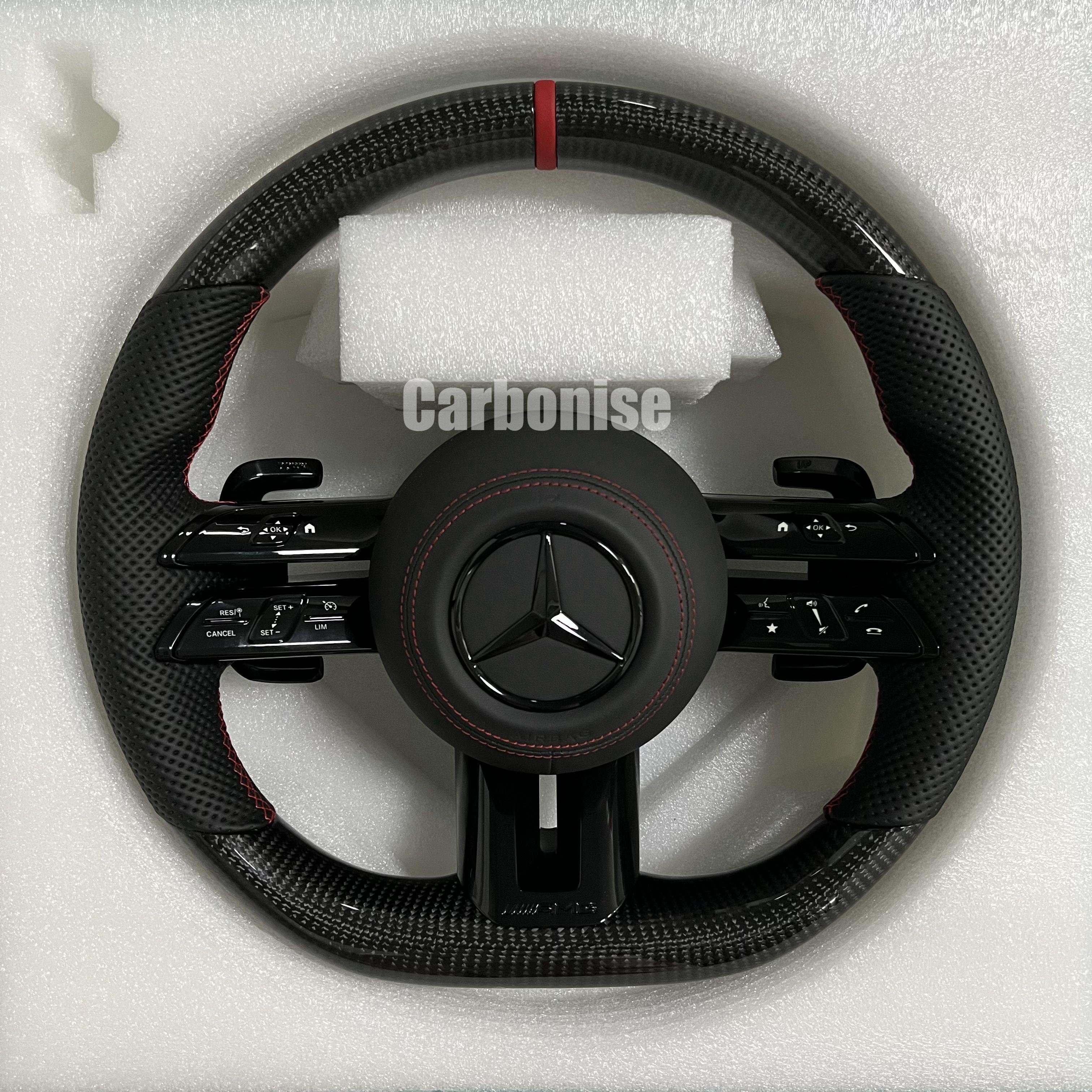 Custom Mercedes-Benz AMG steering wheel featuring high-gloss carbon fiber, a red top racing stripe, and black perforated leather side grips with red stitching.