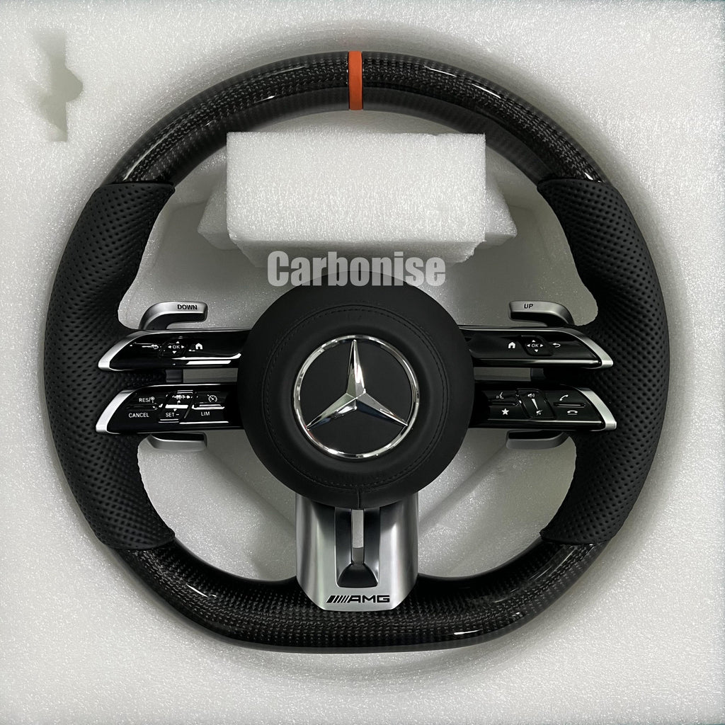 Custom Mercedes-Benz AMG steering wheel featuring high-gloss carbon fiber, a vibrant orange top racing stripe, and black perforated leather side grips.