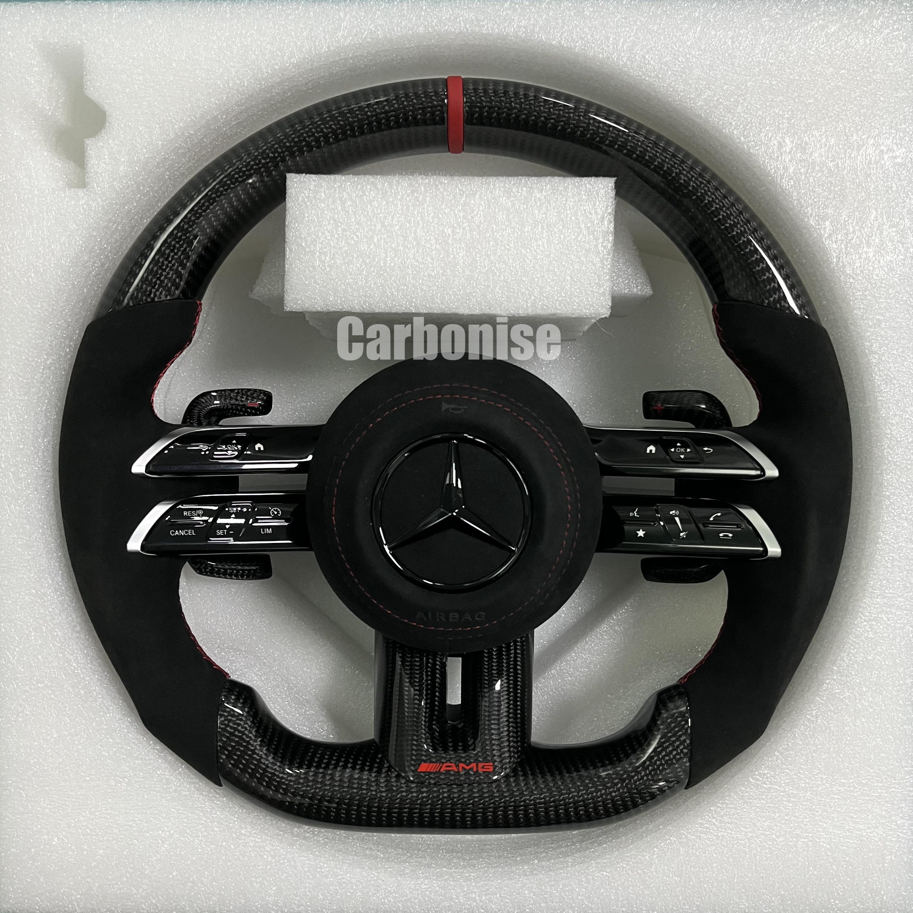 Custom Mercedes-Benz AMG steering wheel featuring high-gloss carbon fiber, a red top racing stripe, and black Alcantara side grips with red stitching.