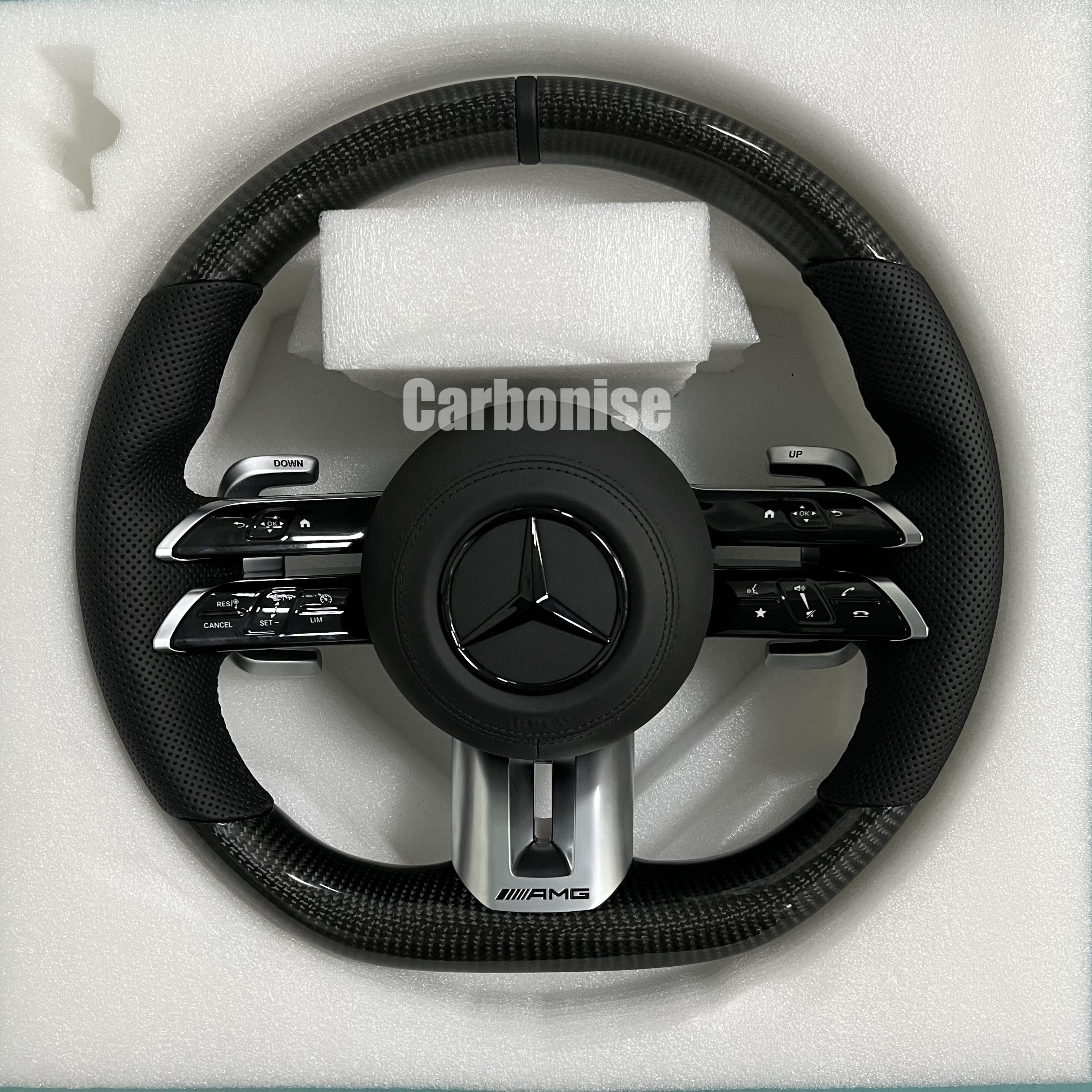 Custom Mercedes-Benz AMG steering wheel featuring high-gloss carbon fiber, black perforated leather side grips, and integrated silver performance controls.