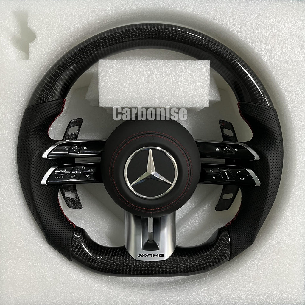 Custom Mercedes-Benz AMG steering wheel featuring high-gloss carbon fiber, black perforated leather grips with red stitching, and silver controls.