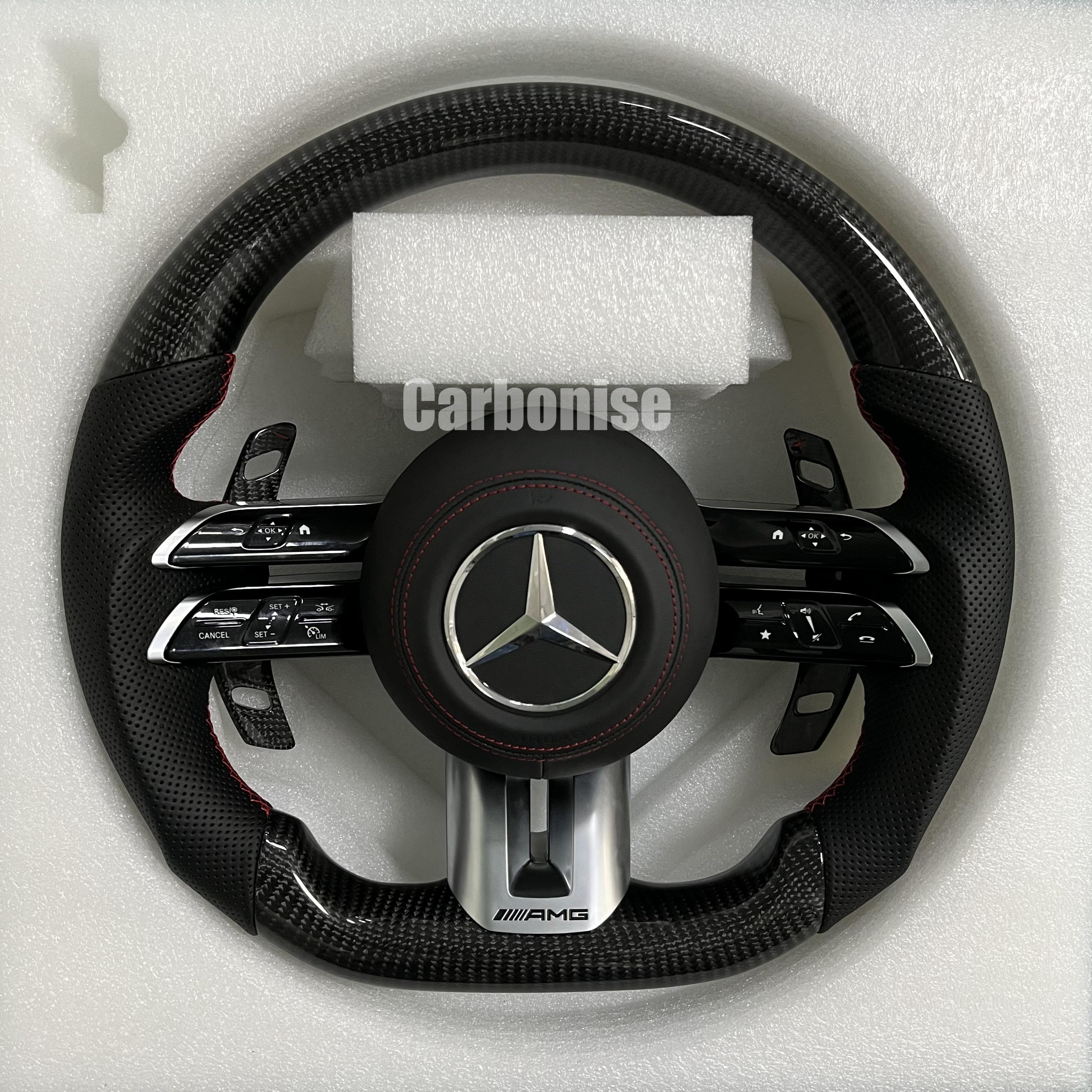 Custom Mercedes-Benz AMG steering wheel featuring high-gloss carbon fiber, black perforated leather grips with red stitching, and silver controls.