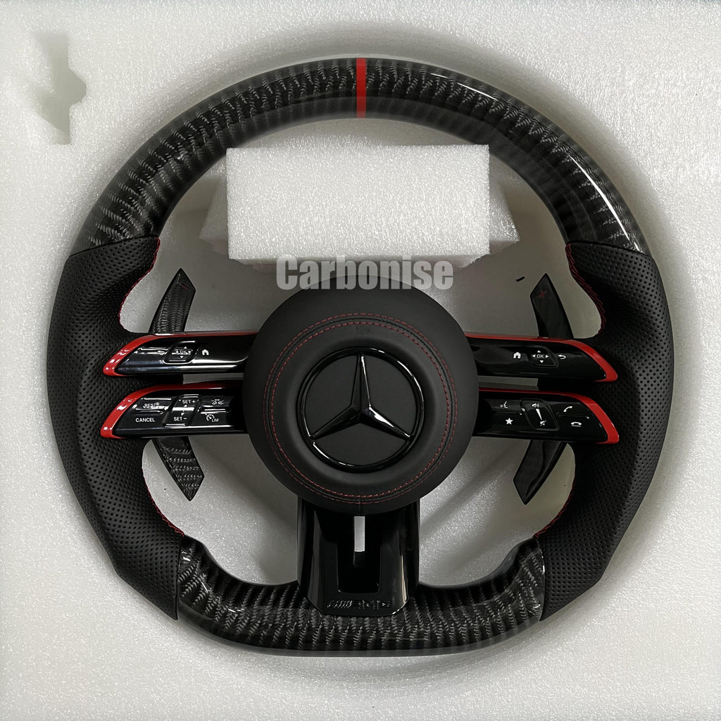 Custom Mercedes-Benz AMG steering wheel featuring high-gloss carbon fiber, a red top racing stripe, and black perforated leather side grips with red accents.