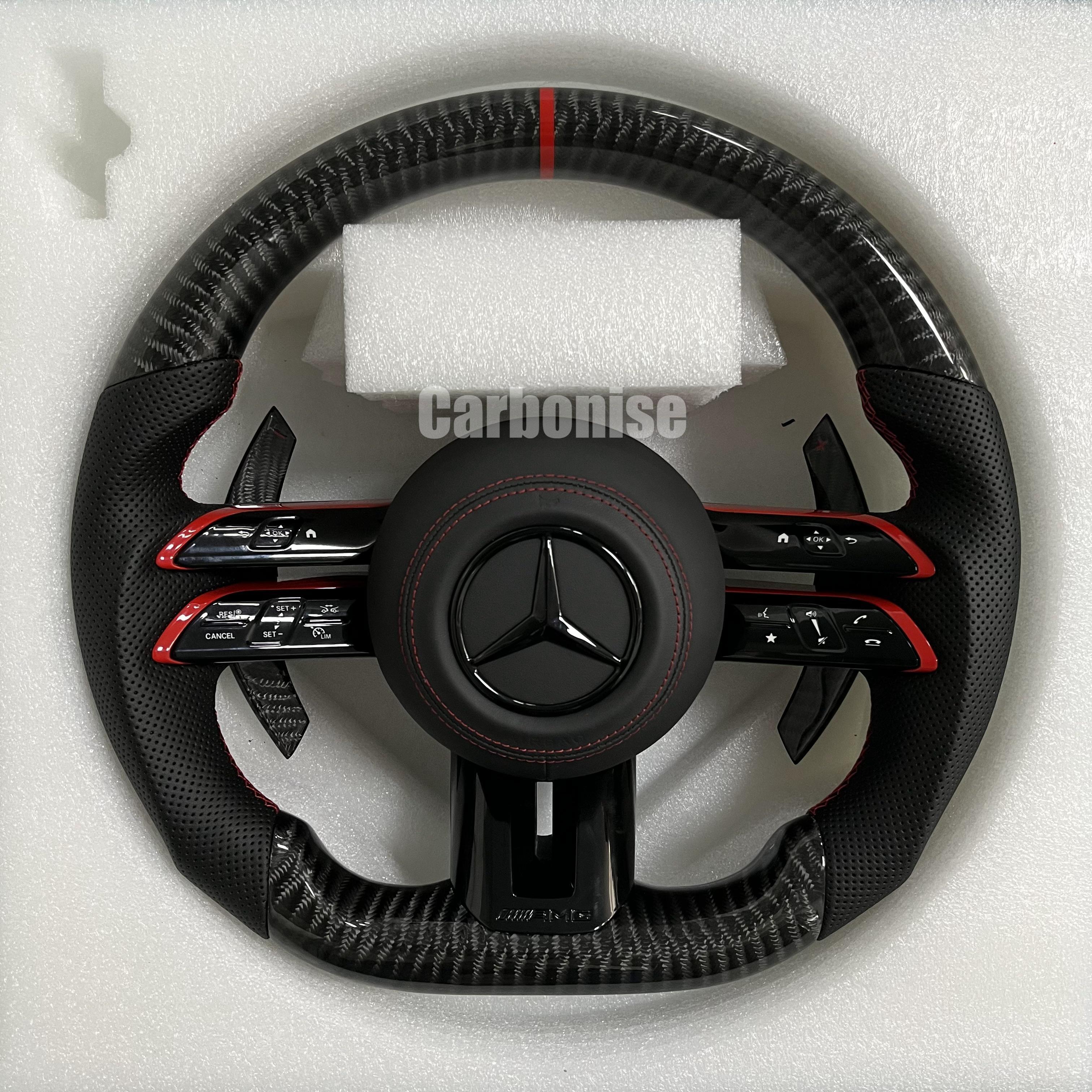 Custom Mercedes-Benz AMG steering wheel featuring high-gloss carbon fiber, a red top racing stripe, and black perforated leather side grips with red accents.