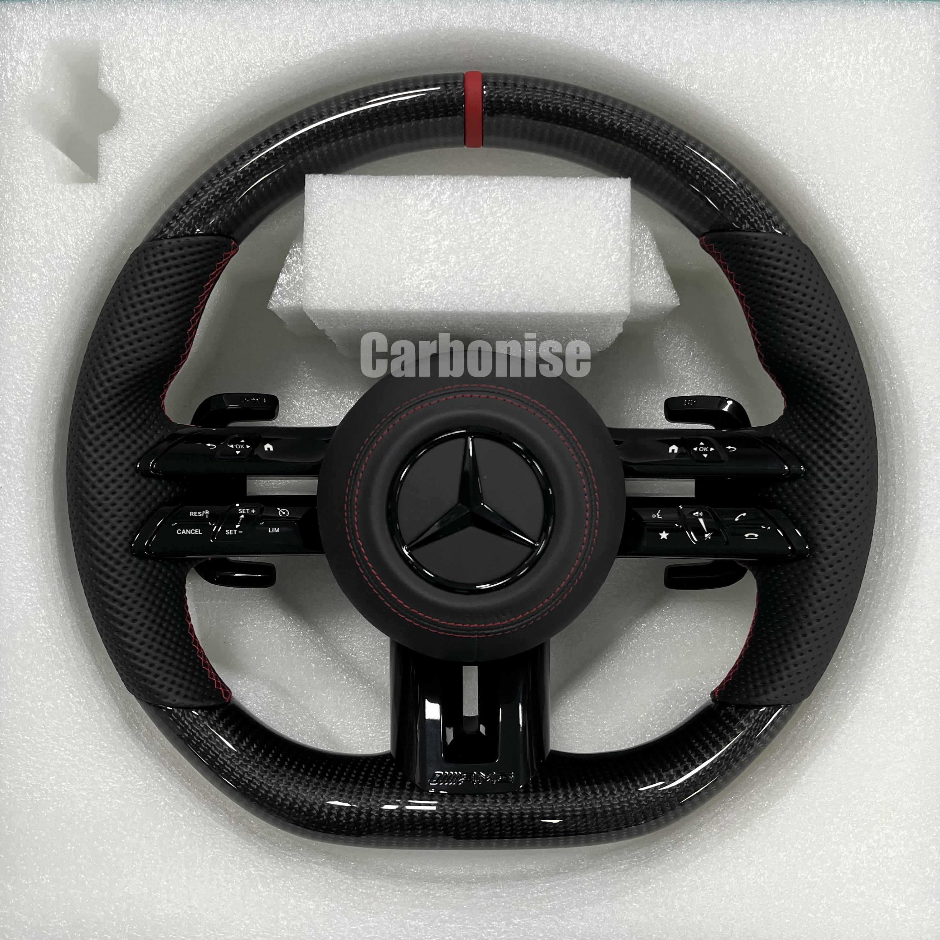 Custom Mercedes-Benz AMG steering wheel featuring high-gloss carbon fiber, a red top racing stripe, and black perforated leather side grips with red stitching.