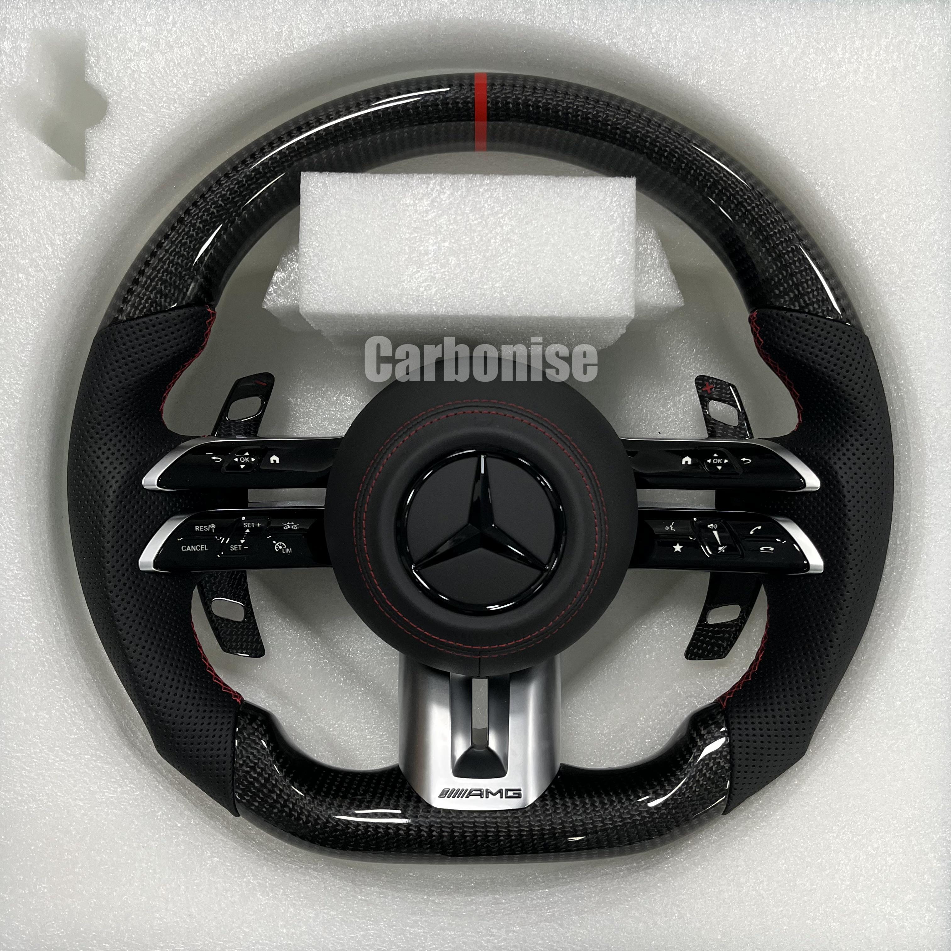 Custom Mercedes-Benz AMG steering wheel featuring high-gloss carbon fiber, a red top racing stripe, and black perforated leather side grips with red stitching.