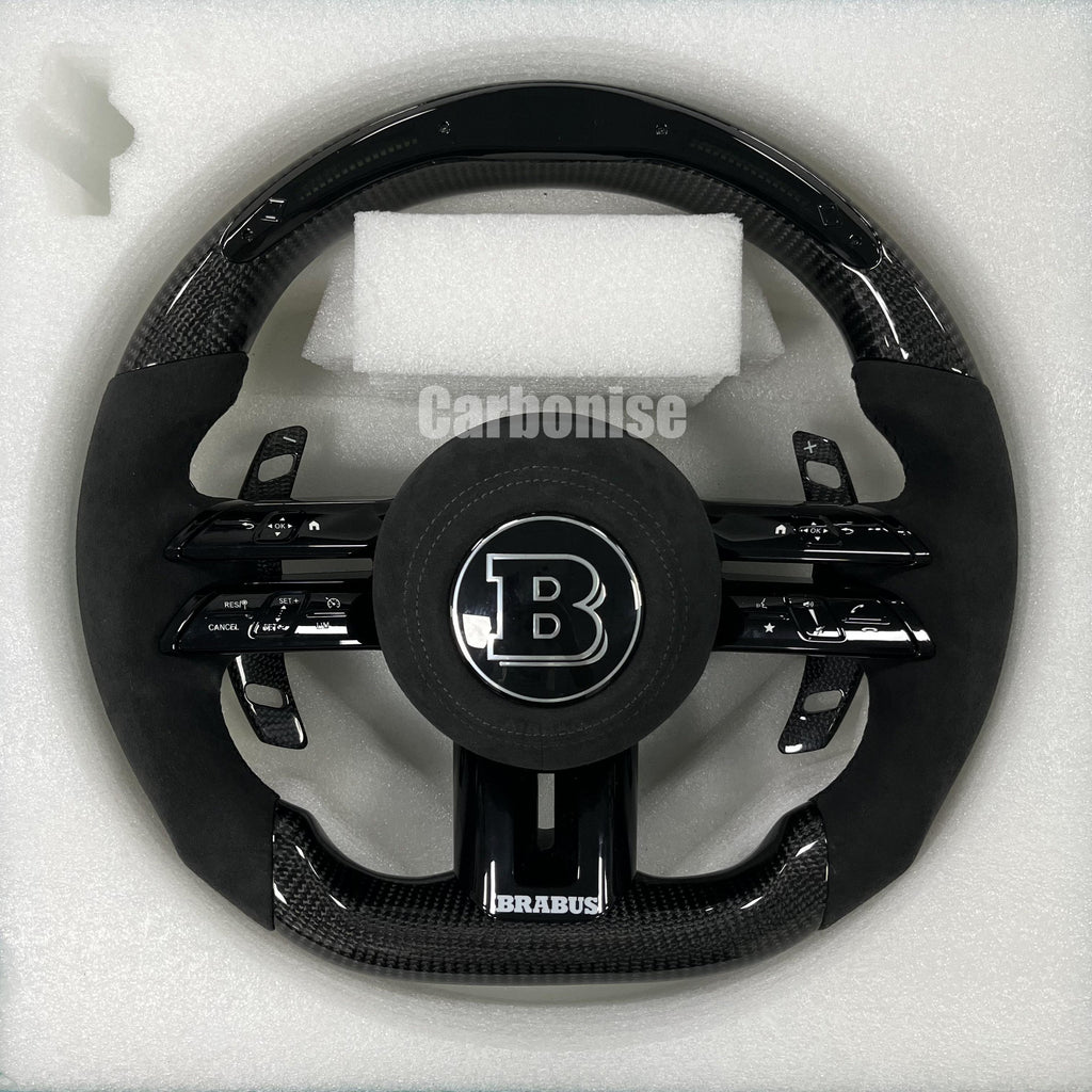 Custom Brabus performance steering wheel featuring high-gloss carbon fiber, black Alcantara side grips, and an integrated Brabus center logo.