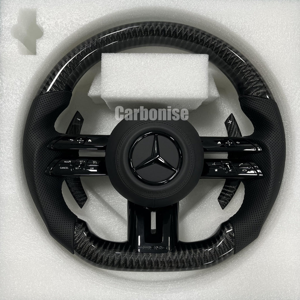 Custom Mercedes-Benz AMG steering wheel featuring high-gloss carbon fiber, black perforated leather side grips, and all-black performance controls.