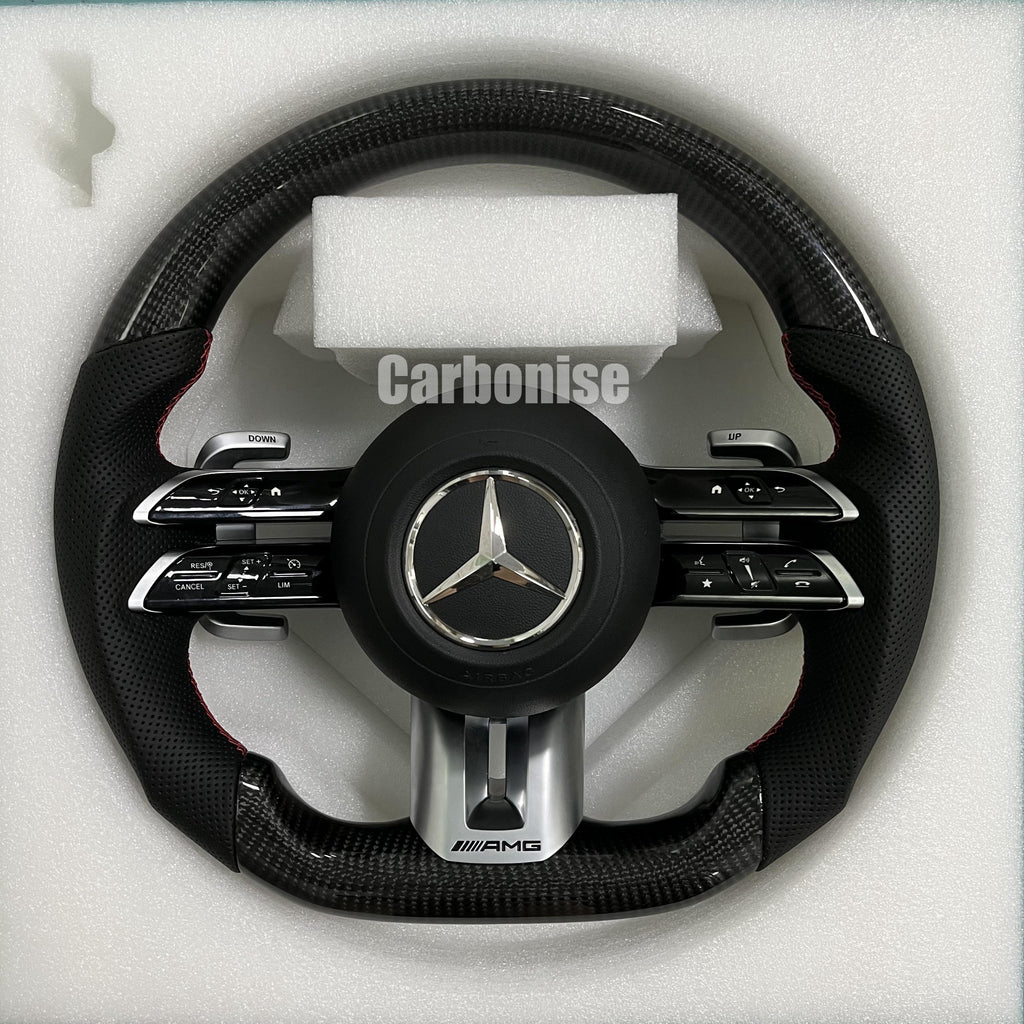 Custom Mercedes-Benz AMG steering wheel featuring high-gloss carbon fiber, black perforated leather side grips with red stitching, and silver performance controls.