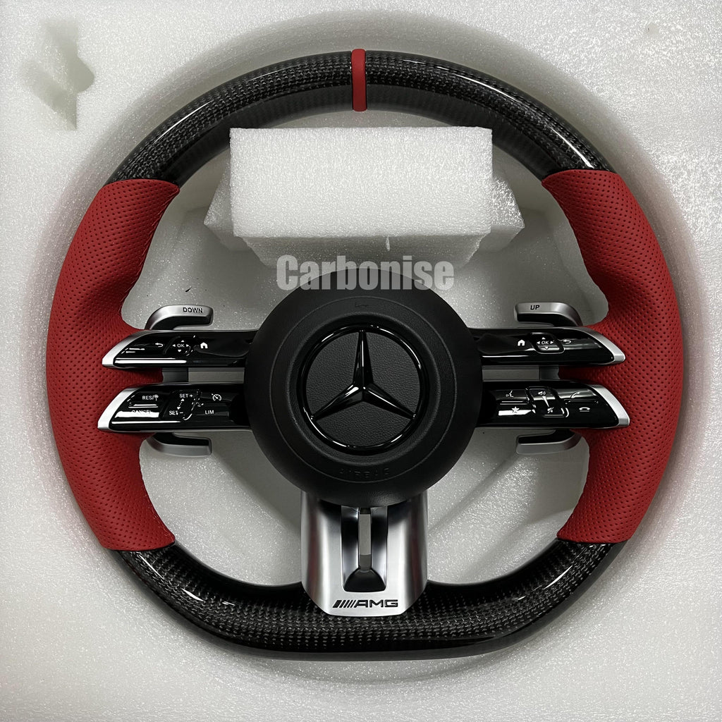 Custom Mercedes-Benz AMG steering wheel featuring high-gloss carbon fiber, a red top racing stripe, and vibrant red perforated leather side grips.