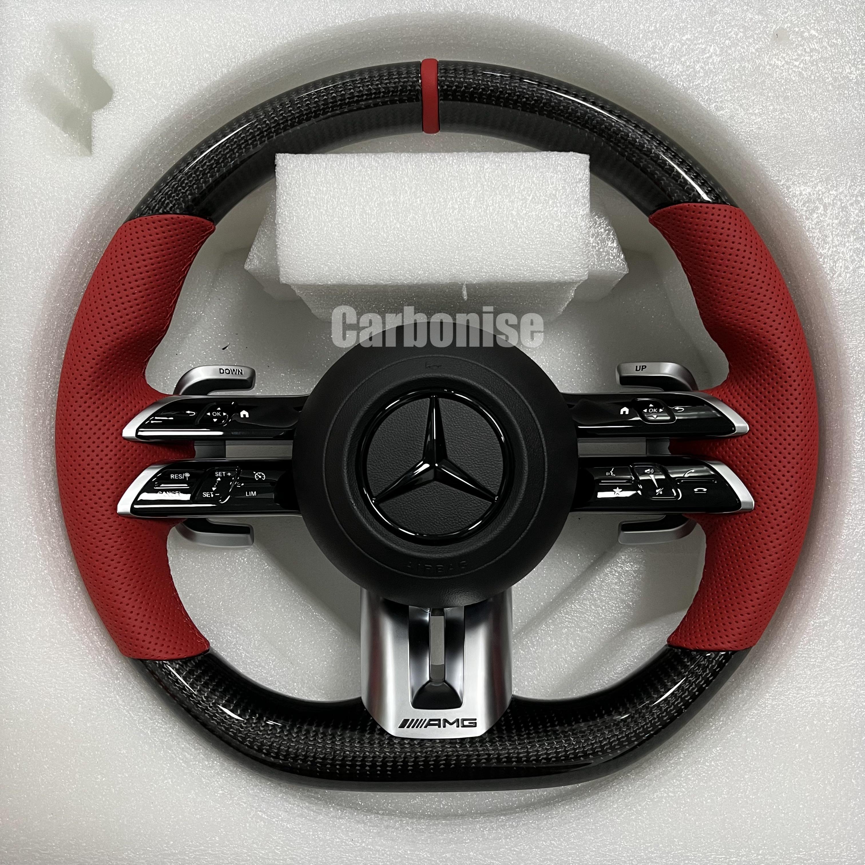 Custom Mercedes-Benz AMG steering wheel featuring high-gloss carbon fiber, a red top racing stripe, and vibrant red perforated leather side grips.
