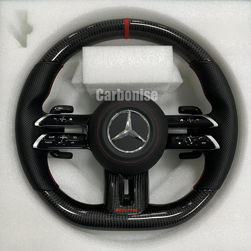 Custom Mercedes-Benz AMG steering wheel featuring high-gloss carbon fiber, a red top racing stripe, and black perforated leather side grips with red stitching.