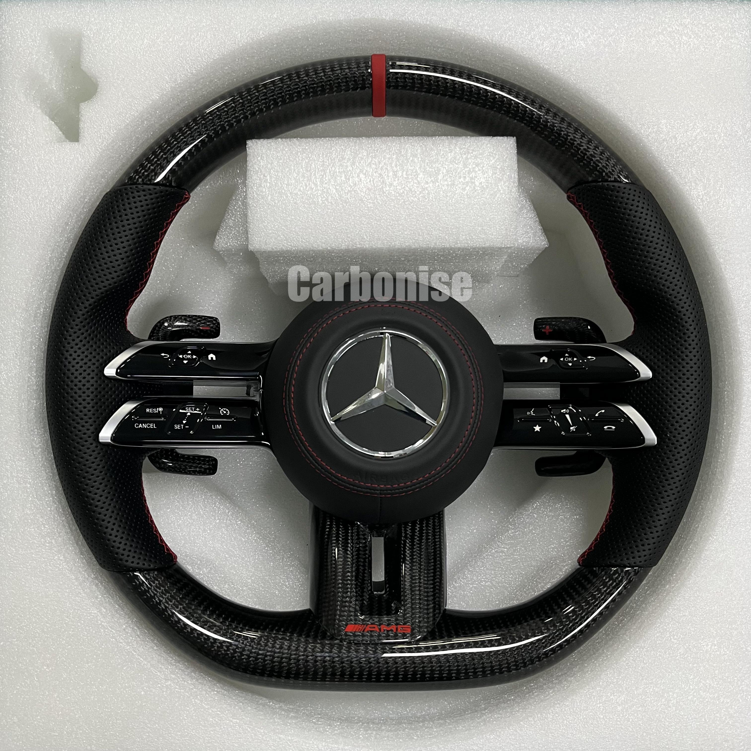 Custom Mercedes-Benz AMG steering wheel featuring high-gloss carbon fiber, a red top racing stripe, and black perforated leather side grips with red stitching.