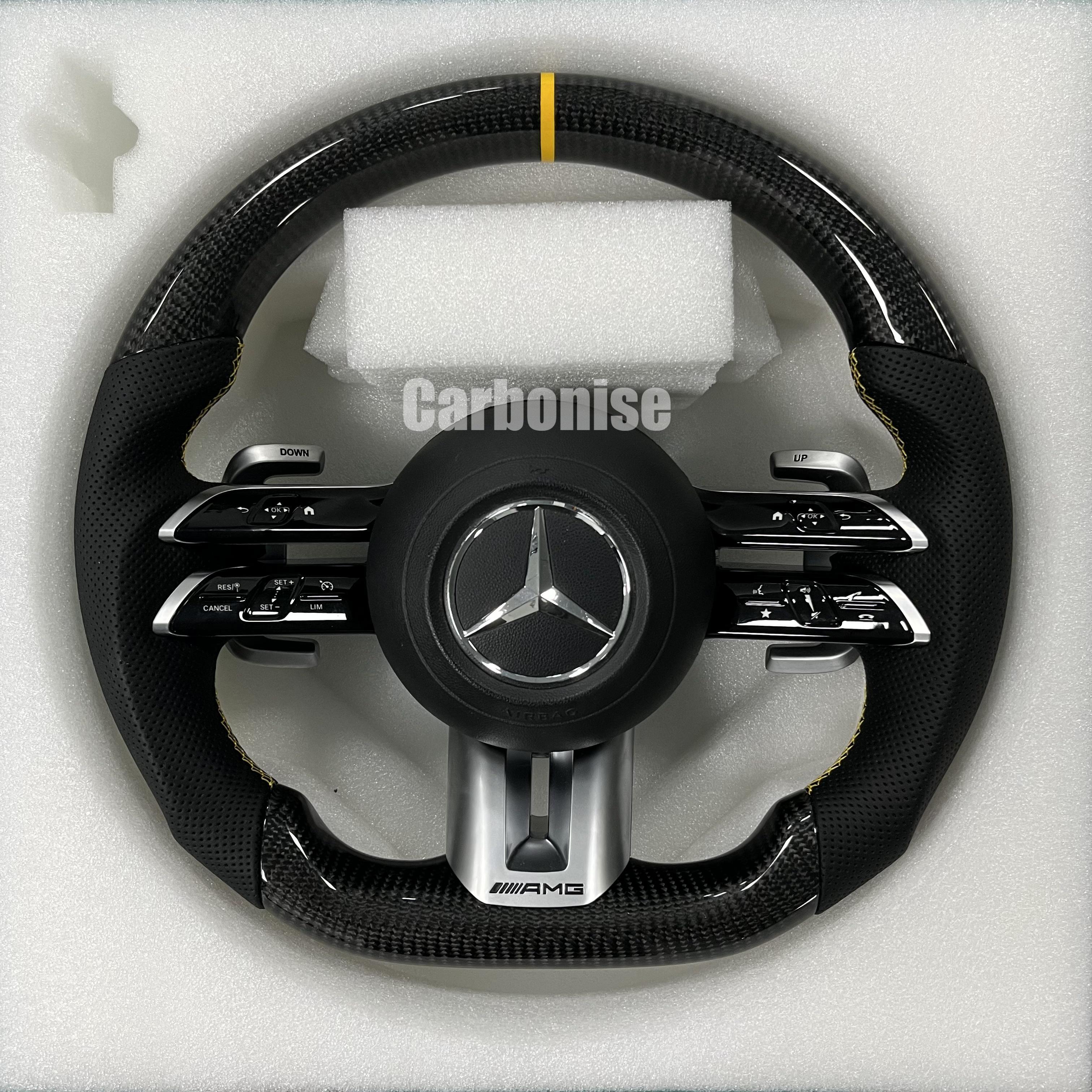 Custom Mercedes-Benz AMG steering wheel featuring high-gloss carbon fiber, a yellow top racing stripe, and black perforated leather grips with yellow stitching.