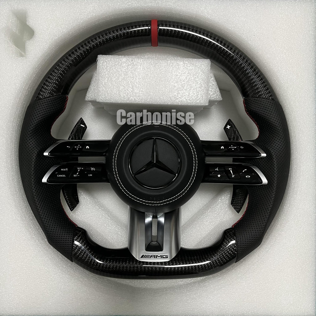 Custom Mercedes-Benz AMG steering wheel featuring high-gloss carbon fiber, a red top racing stripe, and black perforated leather grips with red stitching.