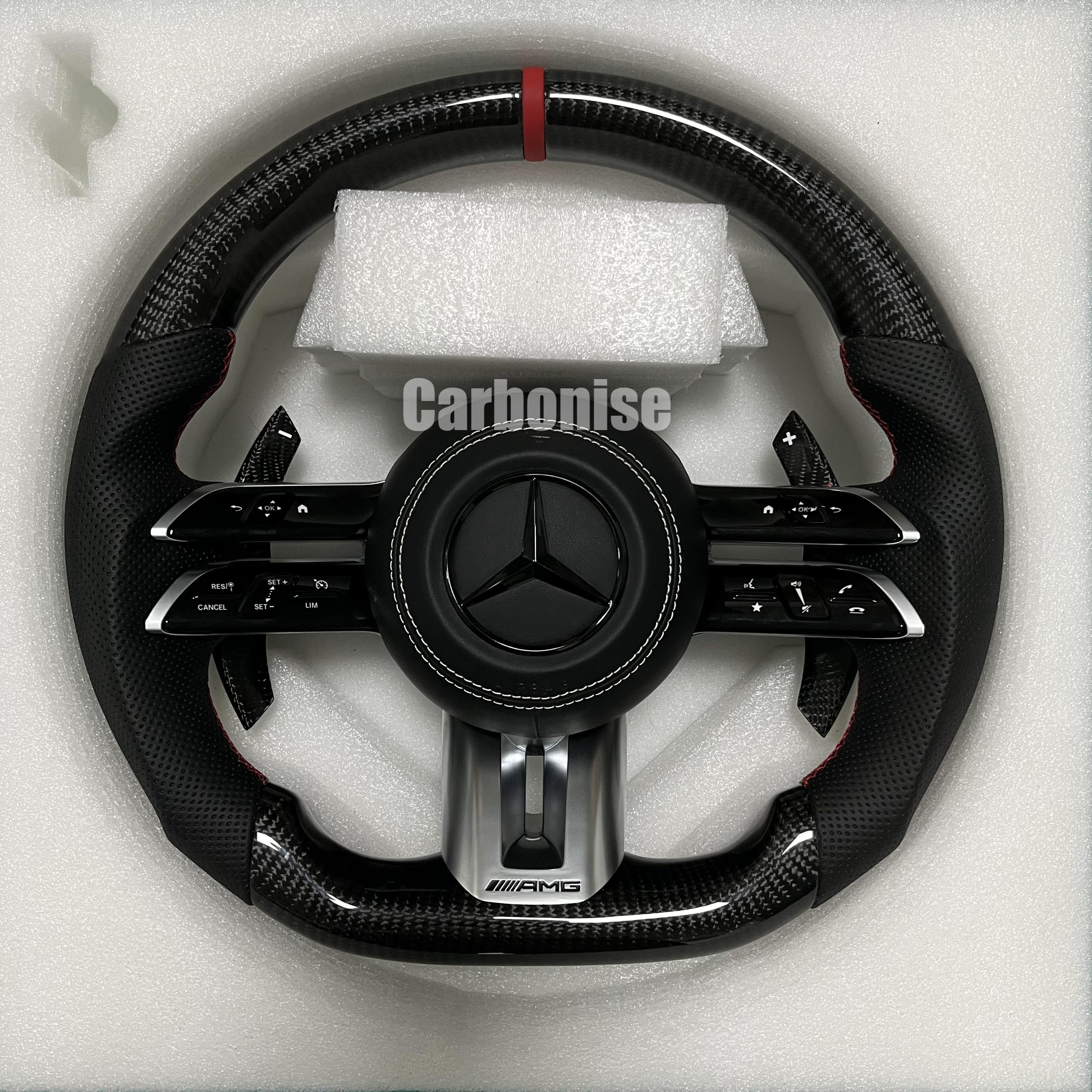 Custom Mercedes-Benz AMG steering wheel featuring high-gloss carbon fiber, a red top racing stripe, and black perforated leather grips with red stitching.