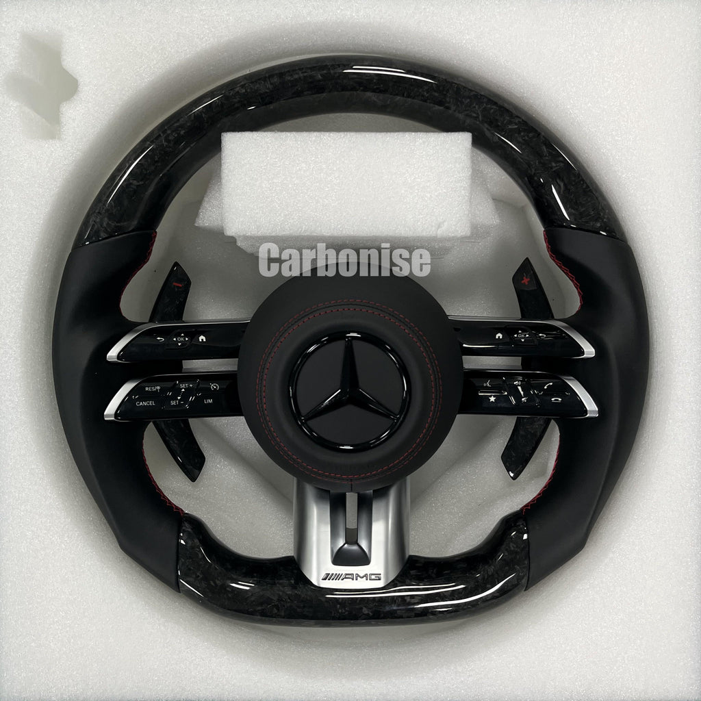 Custom Mercedes-Benz AMG steering wheel featuring high-gloss marbled forged carbon fiber, smooth black leather grips, and red performance stitching.