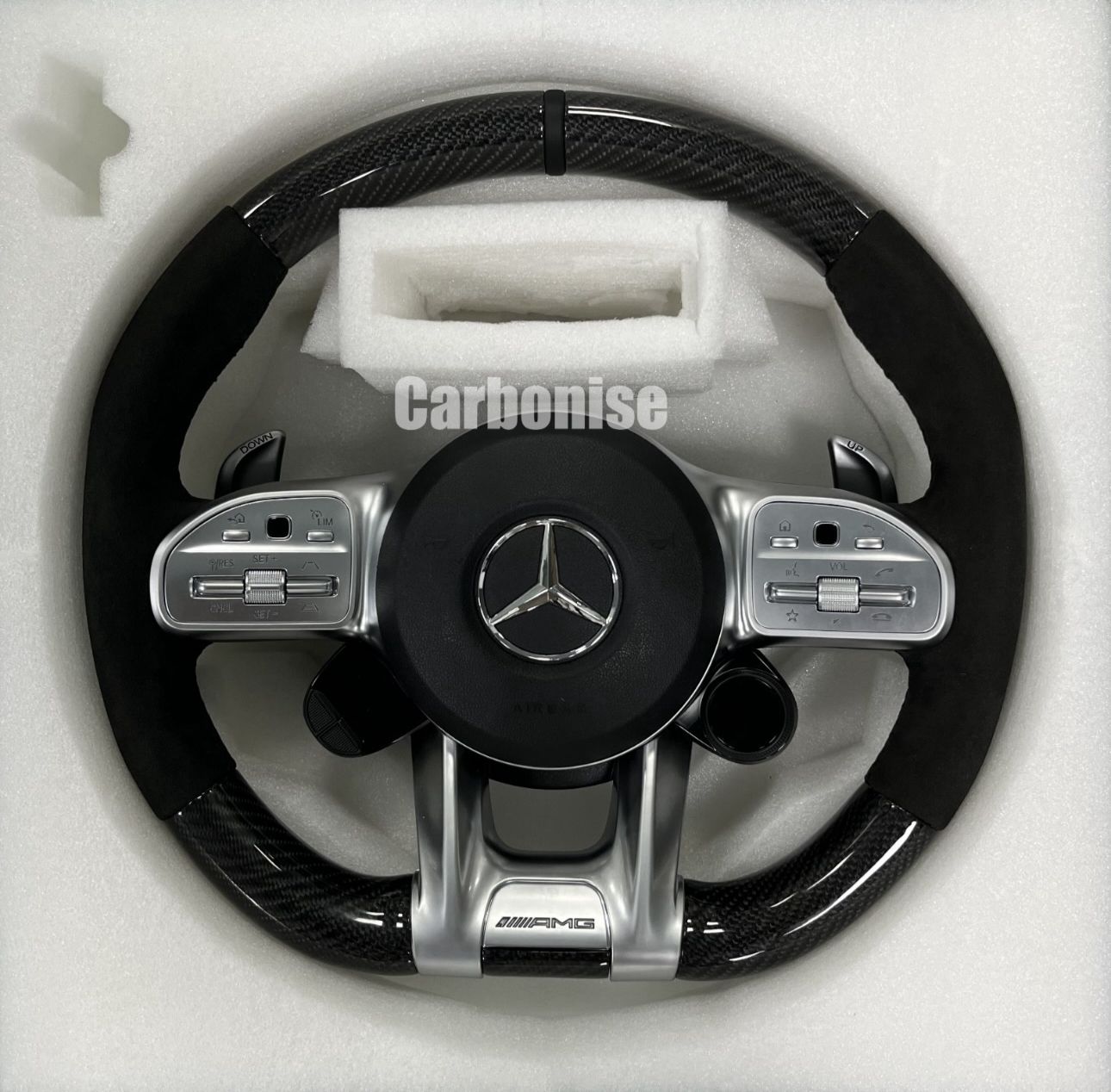 Custom Mercedes-Benz AMG steering wheel featuring high-gloss carbon fiber, black Alcantara side grips, and integrated silver performance controls.