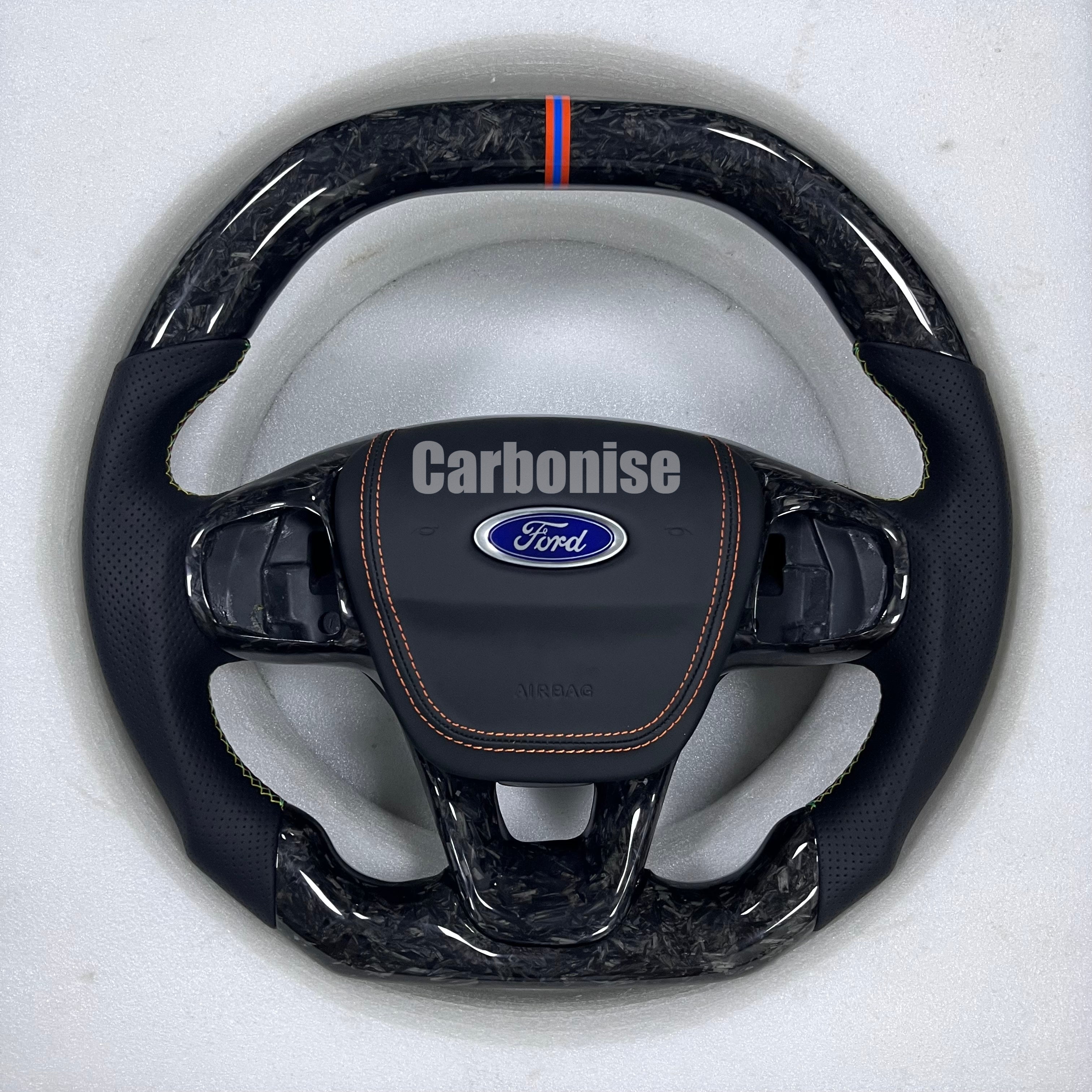 Ford custom steering wheel with forged carbon fibre, perforated leather grips, orange stitching, and centre alignment stripe.