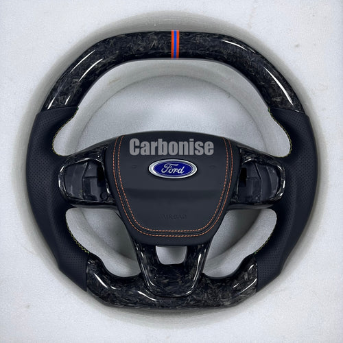 Ford custom steering wheel with forged carbon fibre, perforated leather grips, orange stitching, and centre alignment stripe.