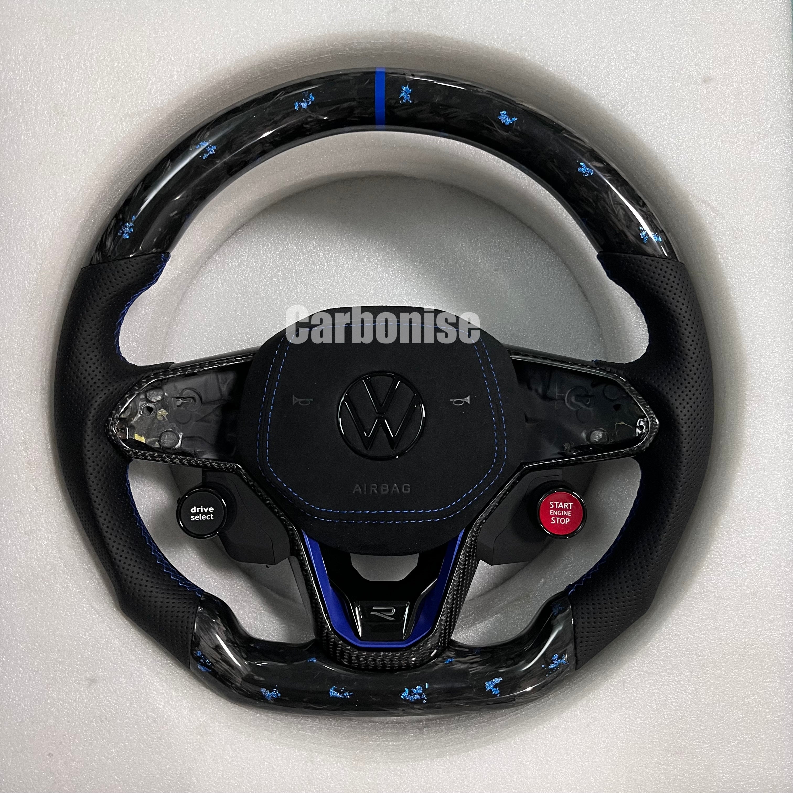 Custom Volkswagen performance steering wheel featuring high-gloss carbon fiber, black Alcantara side grips, and integrated R8-style red start/stop buttons.