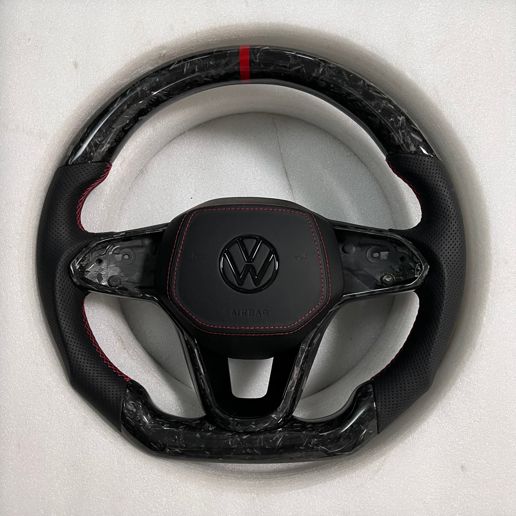 Custom Volkswagen performance steering wheel featuring high-gloss marbled forged carbon fiber, a red top racing stripe, and black perforated leather side grips with red stitching.