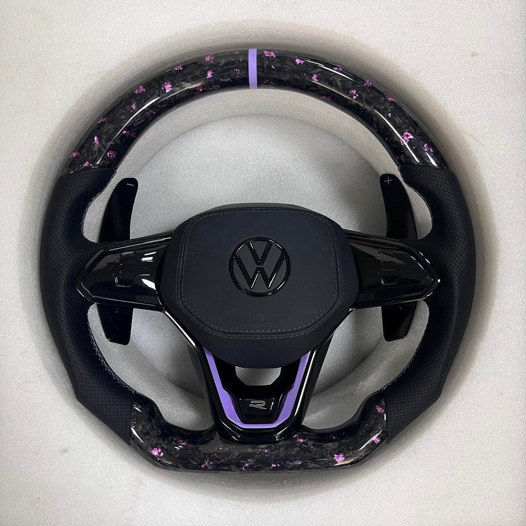 Custom Volkswagen performance steering wheel featuring forged carbon fiber with purple flakes, a lavender top racing stripe, and black perforated leather grips.
